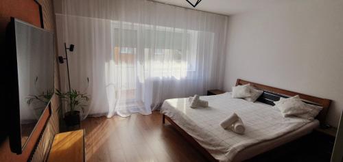a bedroom with a bed with white sheets and a window at Central One Guesthouse in Reşiţa