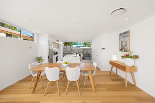 a dining room with white walls and a wooden table and chairs at Noahs Beach House - at Flynns in Port Macquarie
