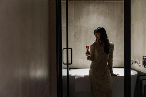 a woman holding a glass of wine in a bathroom at GEMS YUFUIN Hotel and Spa Cafe Bar in Yufuin