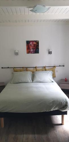 - un lit dans une chambre blanche avec une photo sur le mur dans l'établissement la Heckeliere, à La Houssière