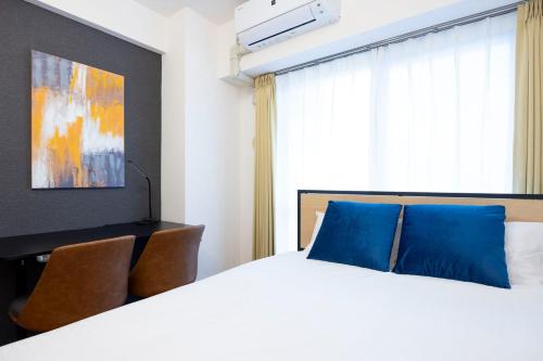 a bedroom with a large bed with blue pillows at Daffitto Mitaka in Mitaka