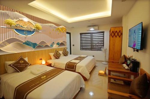 a hotel room with two beds and a television at Tamcoc Golden Shine Homestay & Cafe in Ninh Binh
