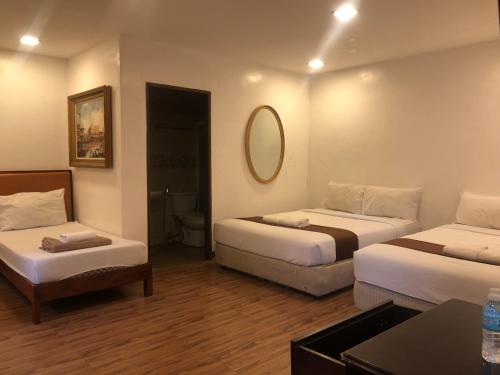 a hotel room with two beds and a mirror at Hortz Hotels And Resorts in Tagaytay