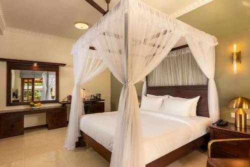 a bedroom with a canopy bed with white drapes at Regal Rivera Villa in Negombo