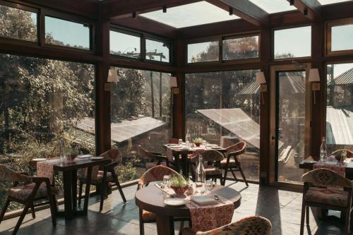 a restaurant with tables and chairs and large windows at Brij Atmanya Bhowali, Nainital, A Luxury Mountain Escape in Nainital