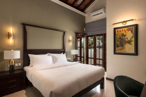 a bedroom with a large white bed and a chair at Regal Rivera Villa in Negombo