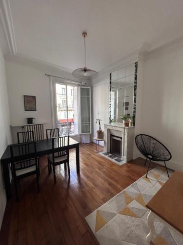 un salon avec une table et des chaises et une cheminée dans l'établissement Appartement Paris Centre village Saint Martin, à Paris