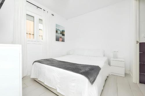 a white bedroom with a bed and a window at Charming House in Chiclana de la Frontera with Terrace in Chiclana de la Frontera