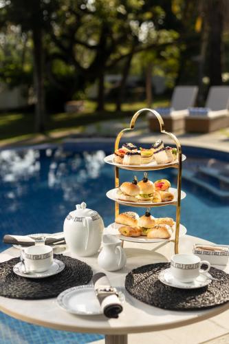 a tray of pastries on a table next to a pool at Regal Rivera Villa in Negombo