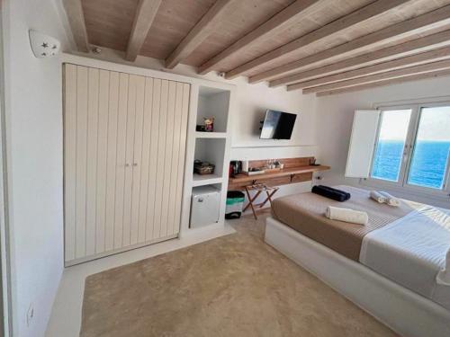 a bedroom with a bed and a desk and a window at White Rock Suites & Villas in Houlakia