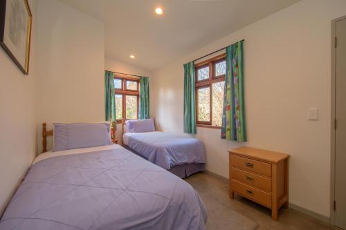 a bedroom with two beds and a dresser and two windows at Willowbrook Country Apartments in Arrowtown
