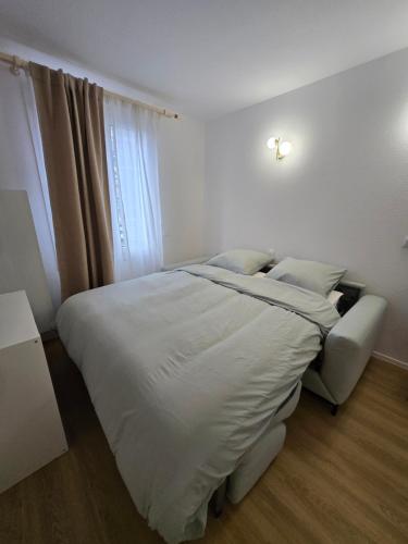 une chambre blanche avec un lit et une chaise dans l'établissement Le Studio Pastel, à Bussy-Saint-Georges