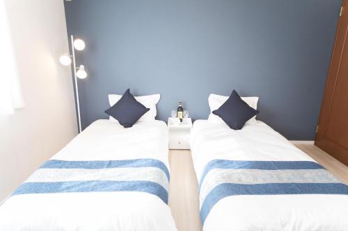 two beds in a room with blue and white stripes at Miraie Yokkaichi Takasagocho in Yokkaichi