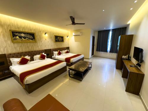 a hotel room with two beds and a television at Hotel Paras Chittorgarh in Chittaurgarh
