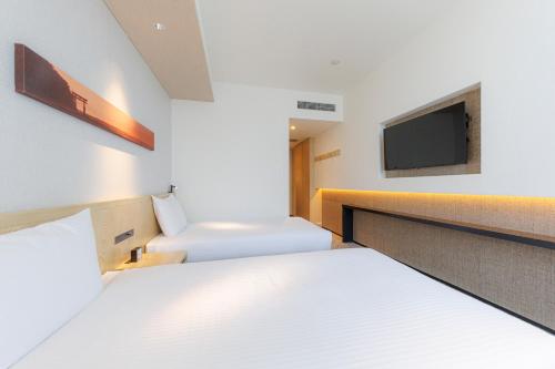a hotel room with two beds and a tv at JR Kyushu Hotel Blossom Shinjuku in Tokyo