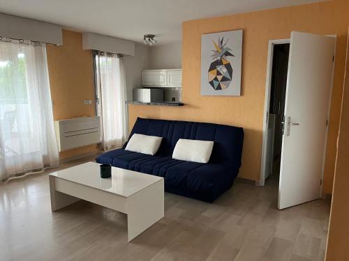 un salon avec un canapé bleu et une table dans l'établissement Appartement Les Palmiers - Vacances Cote d'Azur, à Cannes
