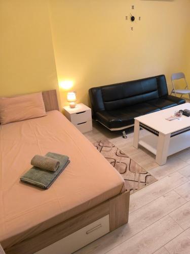 a bedroom with a bed and a black leather couch at Apartment Krasi 1 - with hydrophore system in Pleven