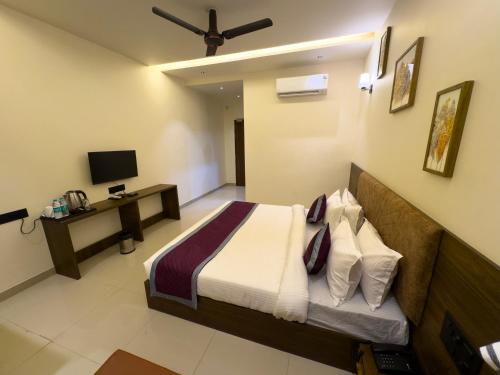 a bedroom with a bed and a desk with a television at Hotel Paras Chittorgarh in Chittaurgarh