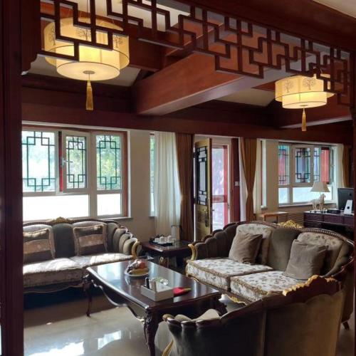 a living room with couches and a table and windows at The Qomolangma Hotel Beijing China in Beijing