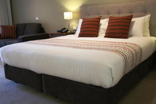 a large bed with red pillows in a hotel room at Bell Tower Inn in Ballarat