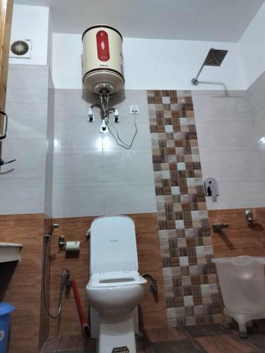 a bathroom with a toilet and a camera on the wall at Shree Ganga Cottages in Raogi