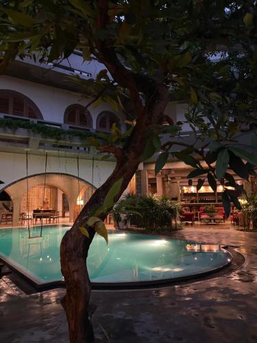 a tree in front of a building with a pool at Olinda Galle in Galle