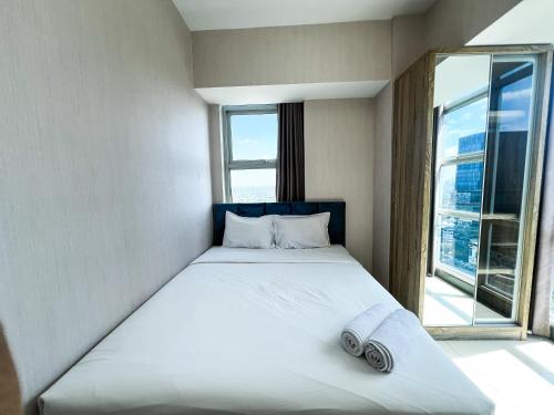 a bed in a room with a large window at Best Choice and Comfortable Living 2BR at Anderson Supermall Mansion Apartment By Travelio in Surabaya