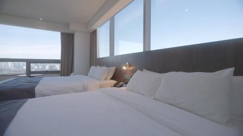 a hotel room with two beds and a large window at Interburgo Hotel Wonju in Wonju