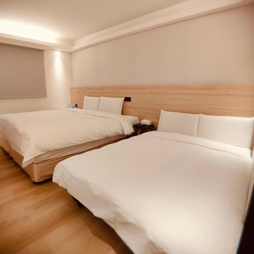 two beds in a hotel room with white sheets at Fooyee Hotel - Yonghe in Yonghe