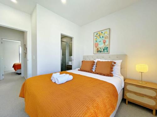 a bedroom with a large bed with an orange blanket at City Serenity 2BR Townhouse vs AC Backyard & Parking in Auckland
