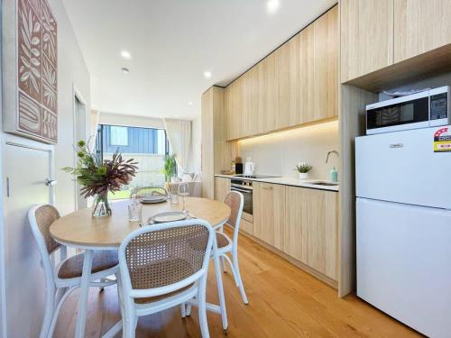 a kitchen with a table and a white refrigerator at City Serenity 2BR Townhouse vs AC Backyard & Parking in Auckland