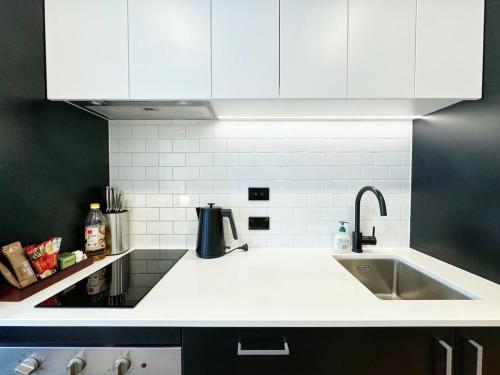 a kitchen with white cabinets and a sink at Lush City Escape - Fresh 1B Studio Near Skytower Pool Gym SaunaSauna in Auckland
