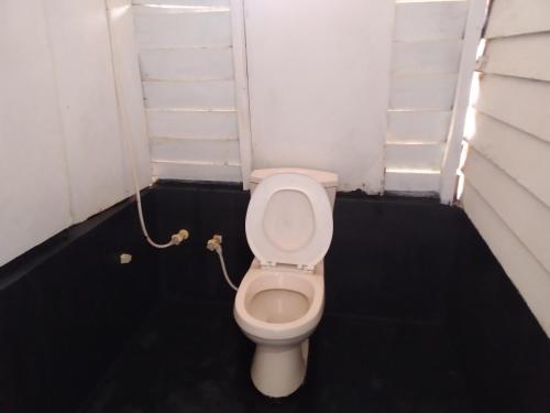 Un baño con un inodoro blanco en una habitación. en Happy Beach Cabana, en Hambantota