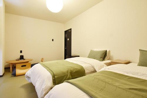 a room with two beds and a table with a table at 民泊富士なんば MinpakuFujiNamba in Osaka
