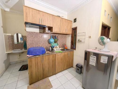 a kitchen with wooden cabinets and a refrigerator at De Monjali Homestay Jogja in Kejayan