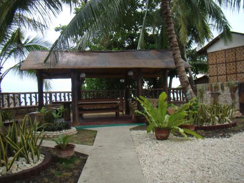 a wooden gazebo with palm trees in a garden at Lagnason's Place in Oslob