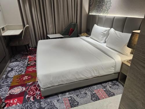 a bedroom with a large white bed and a chair at Crystal Inn in Agra