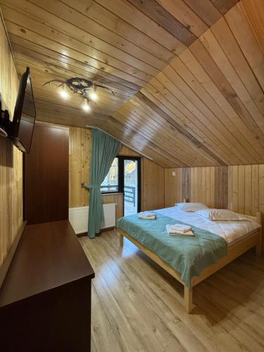 a bedroom with a large bed in a wooden ceiling at Cabana LaMunte in Dorna Arini