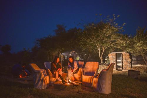 a group of people sitting around a fire at night at The Beehad Sariska in Tehla