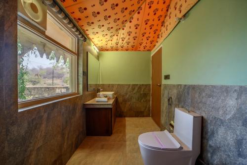 an orange ceiling in a bathroom with a toilet at The Beehad Sariska in Tehla