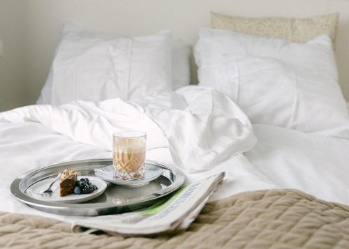 a tray with a plate of food on a bed at Lillan Hotel & Kök in Tampere