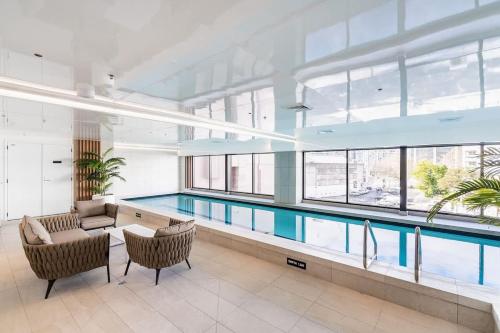 a swimming pool in a large building with a pool at Serene Cityscape 1B Apt Near Skytower vs Gym Pool Sauna in Auckland