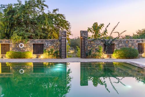 a pool in front of a house with a stone wall at The Beehad Sariska in Tehla