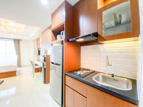 a kitchen with a sink and a refrigerator at Good and Restful Studio at Patraland Amarta Apartment By Travelio in Kejayan