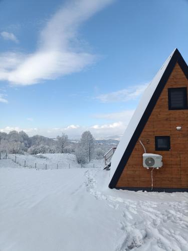 a house in the snow with a snow covered yard at Rock Valley Cabins A-frame in Ibăneşti