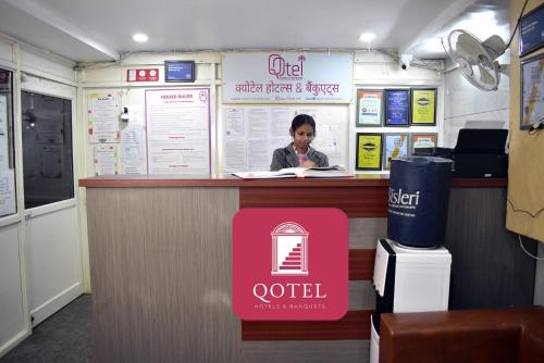 a woman sitting at a counter in a coffee shop at Qotel Hotel Rama Rohini Sector-24 Couple Friendly in New Delhi