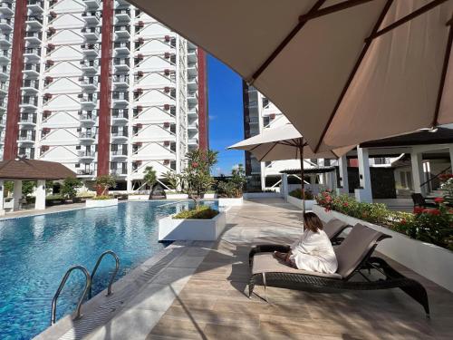 eine Frau, die auf einem Stuhl neben einem Swimmingpool sitzt in der Unterkunft carpe diem staycation in Lapu Lapu City