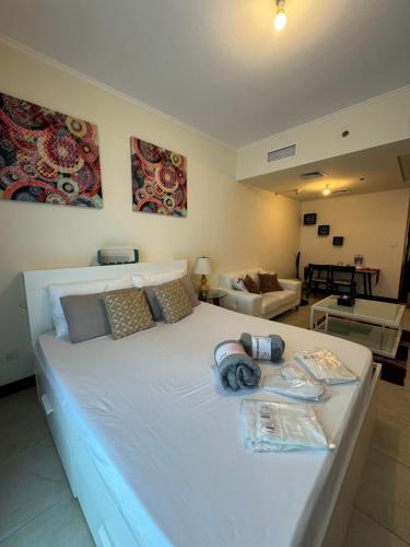 a bedroom with a large white bed and a living room at Click Stay - JLT - Studio & Balcony Lakes view Entire Apartment -RA in Dubai