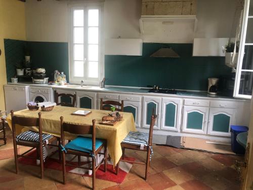 une cuisine avec une table et des chaises dans l'établissement Gîte 2 à 6 personnes près de St EMILION à la campagne, wifi, Clim, piscine, à Lagorce