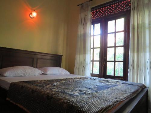 een slaapkamer met een groot bed en een raam bij Belpeak Cottage in Belihul Oya